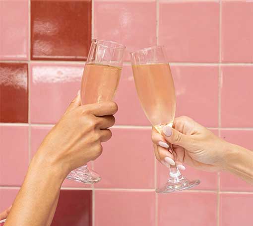 Two champagne glasses clinking. Check out our daily specials at Orange Blossoms!